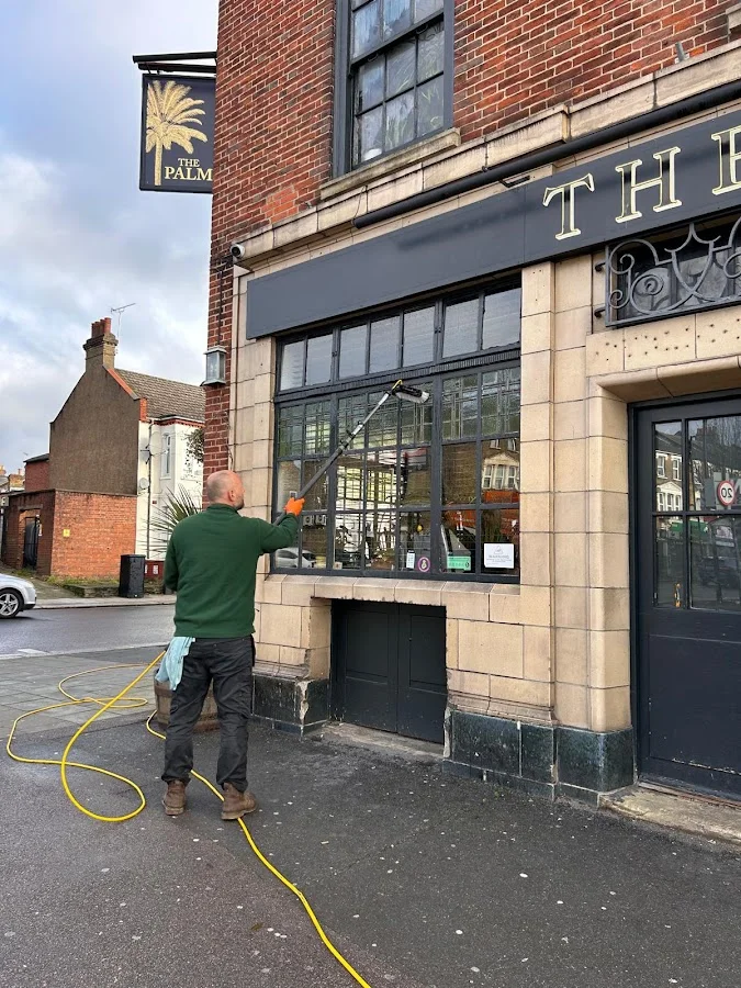 Dritan cleaning large commercial windows at The Palm pub, North London