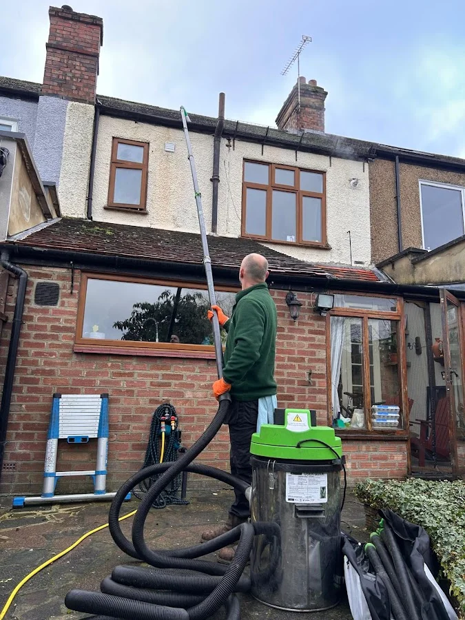 Gutter cleaning with industrial vacuum equipment on terraced house